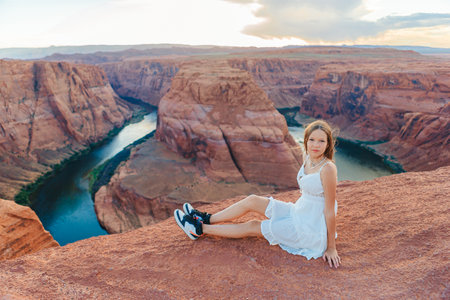 Happy girl on the edge of the cliff at Horseshoe Band Canyon in Page, Arizona. Adventure and tourism concept. Beautiful nature in USAの写真素材