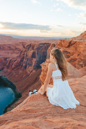 Happy girl on the edge of the cliff at Horseshoe Band Canyon in Page, Arizona. Adventure and tourism concept. Beautiful nature in USAの写真素材