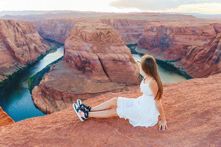 Happy girl on the edge of the cliff at Horseshoe Band Canyon in Page, Arizona. Adventure and tourism concept. Beautiful nature in USAの写真素材