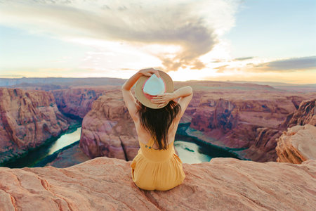 Beautiful woman in yellow dress on the edge of the cliff at Horseshoe Band Canyon in Paje, Arizona....