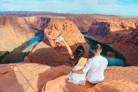 Happy couple on the edge of the cliff at Horseshoe Band Canyon in Paje, Arizona. Adventure and tourism concept. Beautiful nature in USAの写真素材
