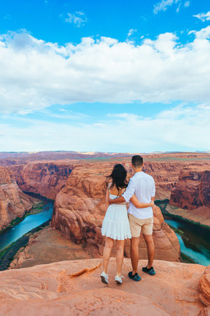 Happy couple on the edge of the cliff at Horseshoe Band Canyon in Paje, Arizona. Adventure and tourism concept. Beautiful nature in USAの写真素材