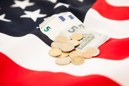 Euro currency and coins lie on the background of the flag of the United Statesの写真素材