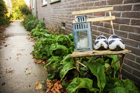 path from the individual brick building with a green line of plants with a chair in the foreground as garden itemsの写真素材