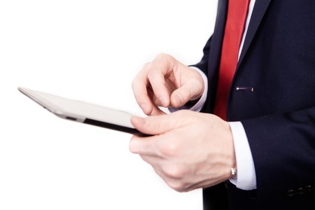 A man wearing a tie is working on a tablet computer on an isolated white background.の写真素材