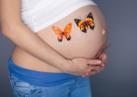 caucasian pregnant woman stress anxious with butterfly in the stomach isolated studio on gray background.の写真素材