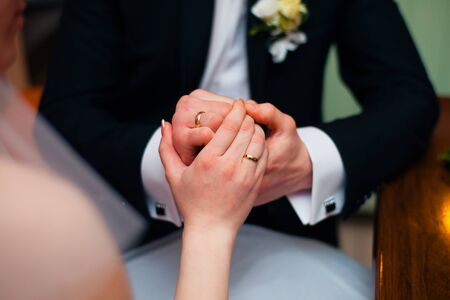 Hands of wedding couple putting golden rings to finger of each otherの写真素材