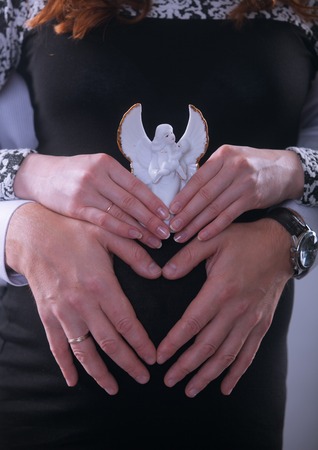 Pregnant Woman holding her hands in a heart shape on her baby bump. Pregnant Belly with fingers Heart symbol. Maternity concept. Baby Shower.の写真素材
