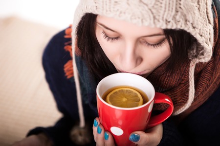 Woman enjoying a large cup of freshly brewed hot tea as she relaxes on a sofa in the living room.