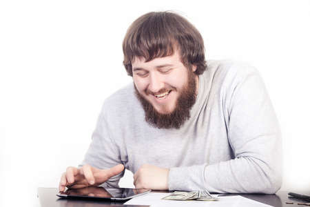 Accountant using a tablet computer, man smiling sitting at a desk, Internet surfingの写真素材