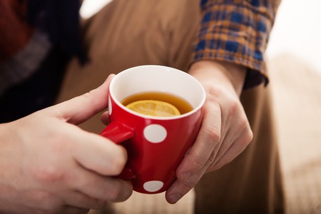 Close-up of male hands holding red mugの写真素材