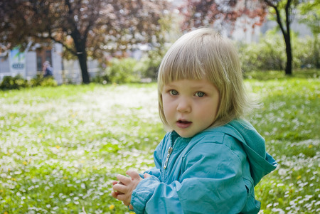 Baby girl standing in a field playing with flowersの写真素材