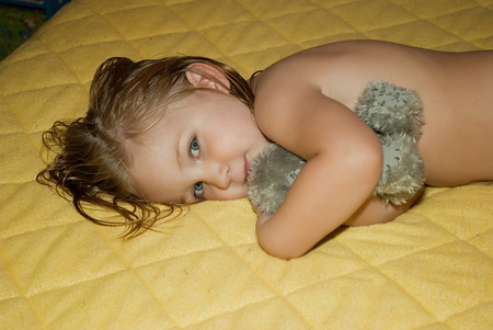 Cute baby girl lying on yellow backgroundの写真素材