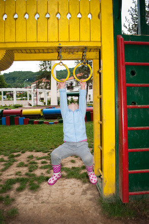 Little girl is hanging on gymnastic ringsの写真素材