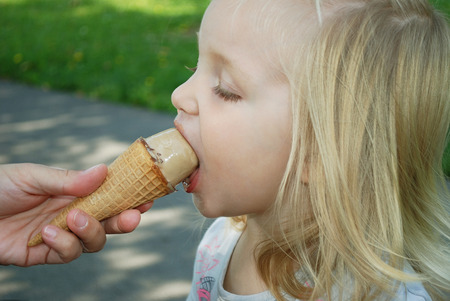Little girl is eating ice creamの写真素材