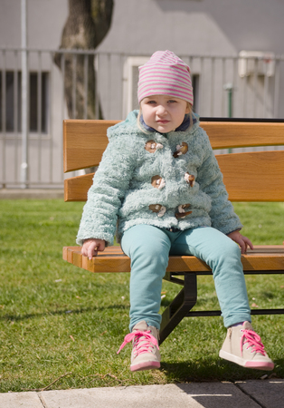 Little girl is sitting on a benchの写真素材