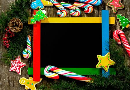 Winter frame:wooden board surrounded by homemade cookies and lollipopsの写真素材