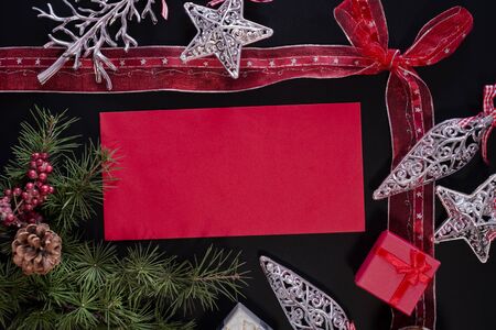 Winter frame: christmas decoration surrounding red envelope on black backgroundの写真素材