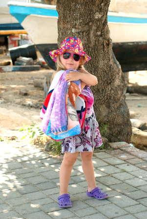 Cute little girl standing on sidewalk ready for beachの写真素材