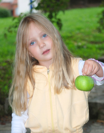 Pretty little girl is holding an appleの写真素材