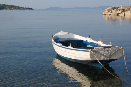 A small fishing boat is floating over a calm seaの写真素材