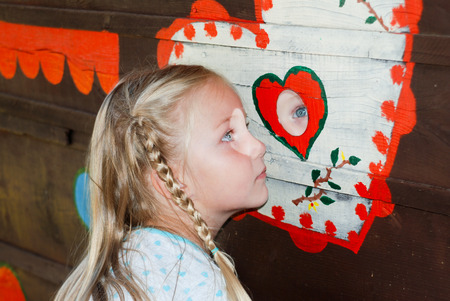 Pretty little girl is looking through the mirrorの写真素材