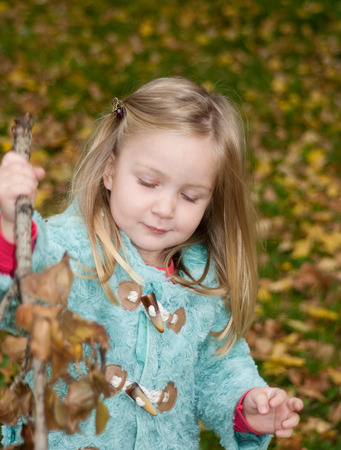 Pretty little girl is holding a tree branchの写真素材