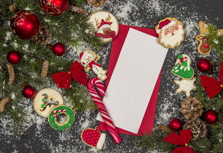 Winter frame: cookies and christmas decoration surrounding red envelope on black backgroundの写真素材