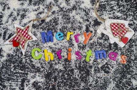 Colorful christmas title surrounded with snow on black backgroundの写真素材