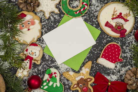 Winter frame: cookies and christmas decoration surrounding small green envelope on black backgroundの写真素材