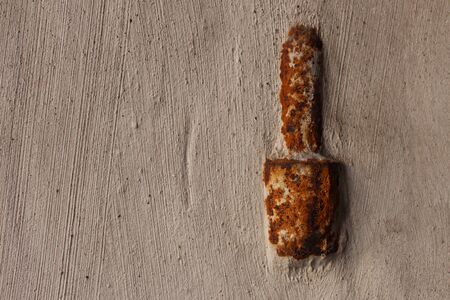 Part of a rusty old door hinge in a plaster wall