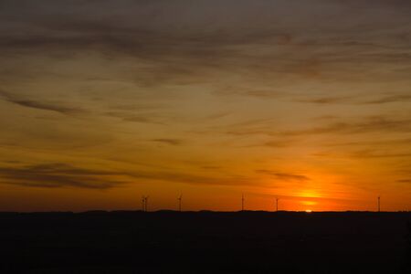Wind turbines producing clean energy on the horizon during sunset with text spaceの写真素材