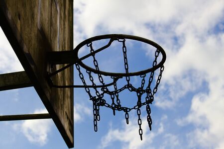 Old basketball chain basket close up view before cloudy sky