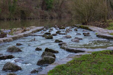 Fish ladder or stairs beside a weir to help fish to swim upstream and overcome a weir at a riverの写真素材