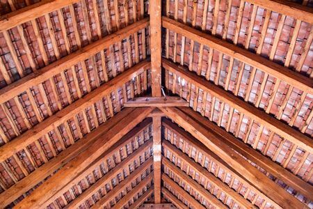 Wooden roof ridge in a old attic with view of the roof shingles