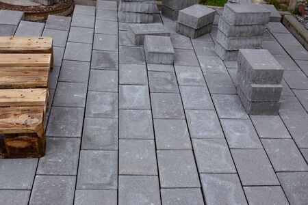 Concrete paver blocks laid beside a building, some paving stones are stacked for future use