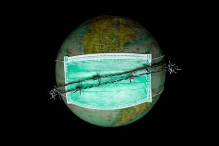 World or earth alone in outer space wearing a medical mask to protect from world pollution and barbed wire as a symbol of not being able to leave earth, concept of protecting the world, Selected focus on mask on blurred globeの写真素材