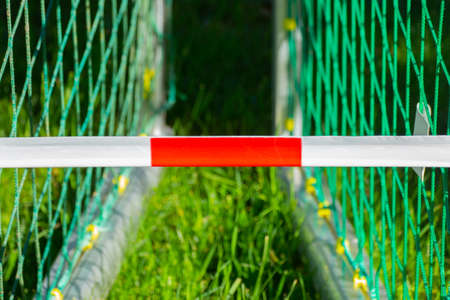 Red and white barrier tape in front of two soccer goals, concept of soccer or football fields closedの写真素材