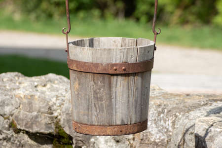 Close up of a old antique wooden bucket hanging over a wellの写真素材