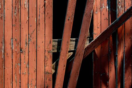 Red wooden plank wall with damaged planks hanging downの写真素材
