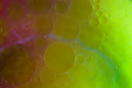 Blurred soft focus of oil spheres in water with color transition from green to orange tones for...