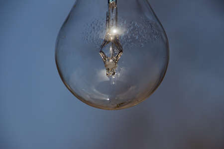 Close up of a vintage lightbulb hanging outdoors with condensation droplets inside