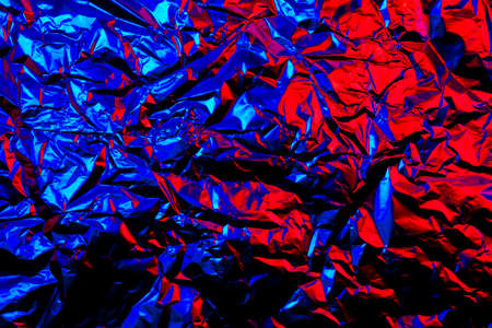 Abstract red and blue aluminum wrinkled foil background texture reflecting red and blue lightの写真素材