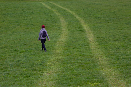 Unidentifiable woman walking in the grass, leaving the trailの写真素材