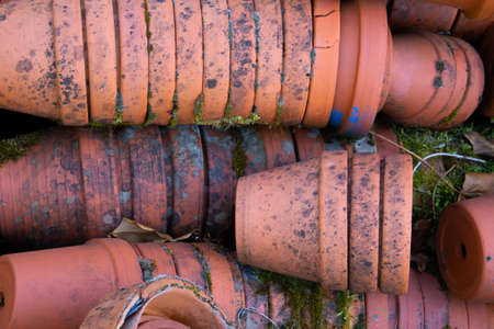 Dirty stacked terracotta flower pots laying on the floor of a greeneryの写真素材