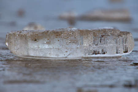 Side view of ice block laying on ice surface, selective focus
