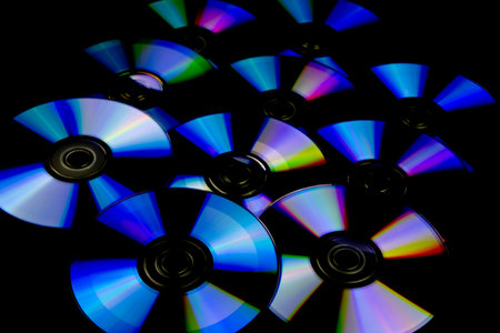 CD and DVD isolated on black background with colorful light reflectionsの写真素材