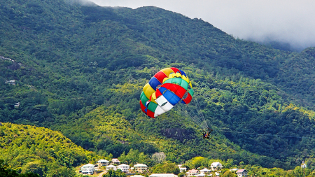 Colorful Parasailing screen in front of the green mountains on the coast of Seychellesの写真素材