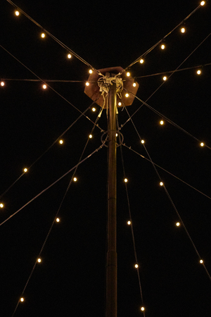 an old lantern pole is decorated linearly with a beautiful chain of lights and shines before a black...