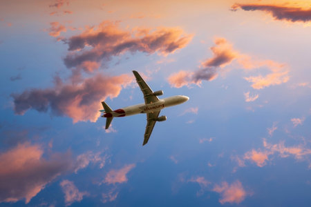 Eurowings airbus plane flies through light pink clouds in the blue evening sky towards the sunset